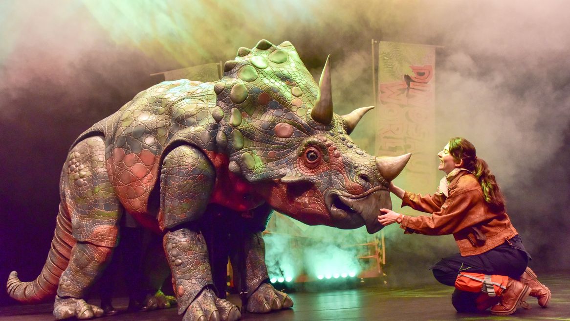 A woman strokes the nose of a Triceratops puppet