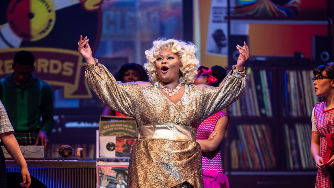 A woman with blonde hair sings in a record store