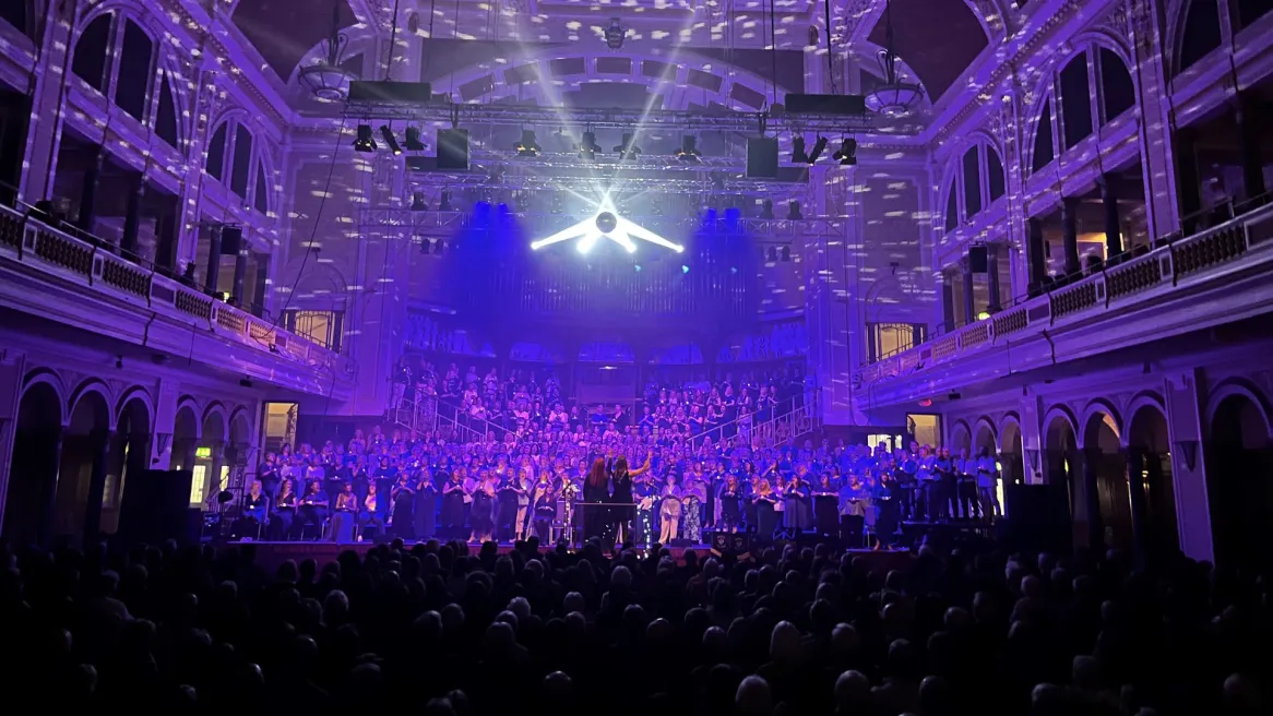 A choir performs on a stage in front of a busy audience