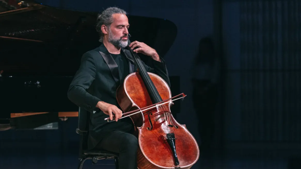 Man in a black suit playing a cello 