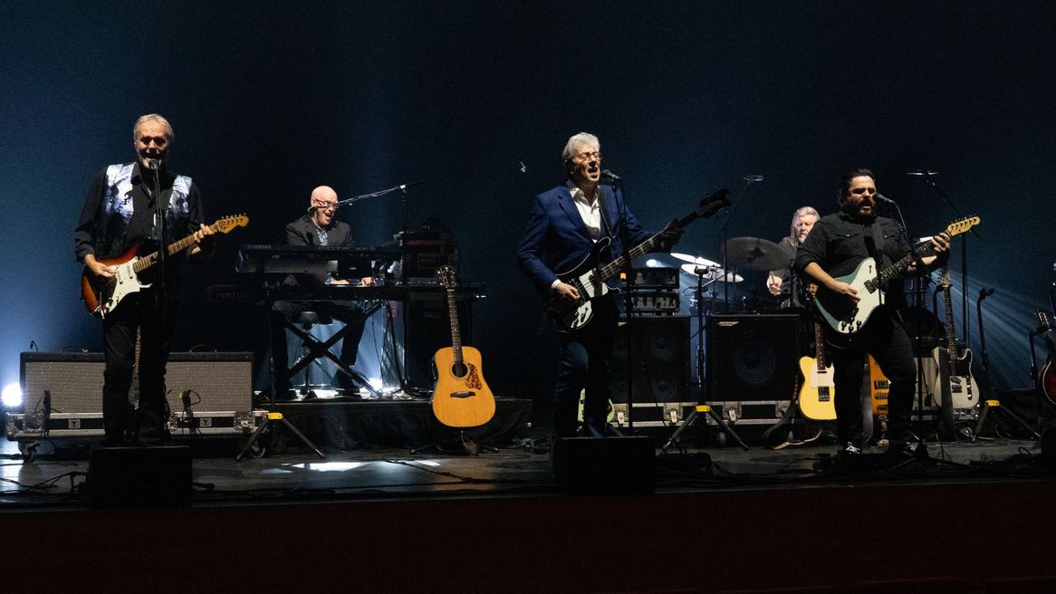 Five musicians on stage together performing live.